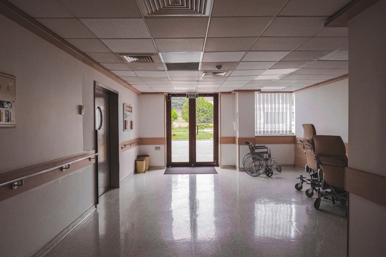 Wheelchair waiting in an accessible building corridor beside an elevator and glass entrance doors — the access route ADA elevator compliance protects