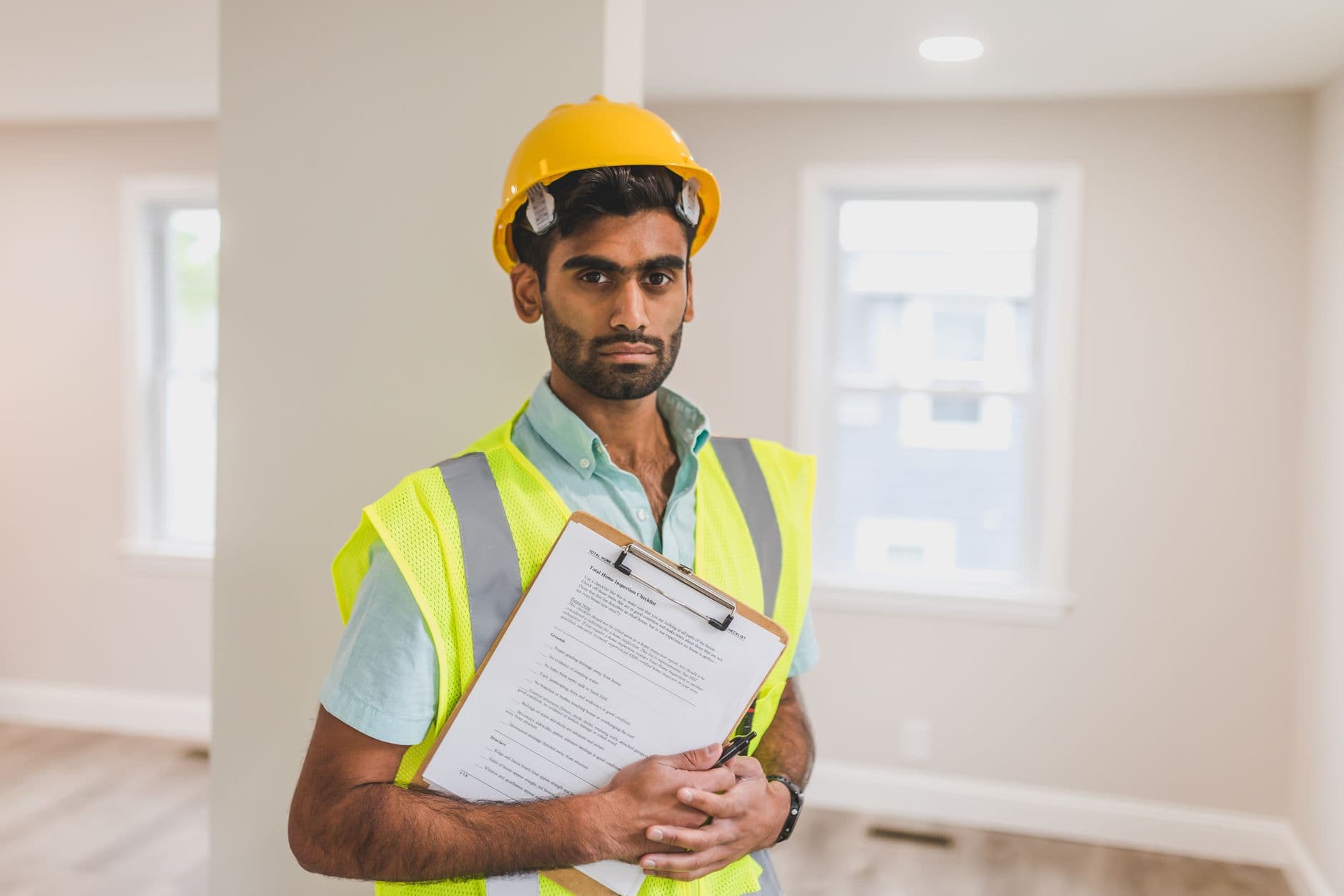 An elevator inspector reviewing equipment in a machine room with a clipboard